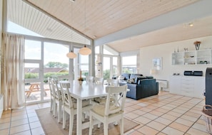 A spacious living area with a dining table, white chairs, a blue sofa, and a kitchen area with white cabinets and a countertop. - Awesome home in Sjølund with kitchen (Sjølund)