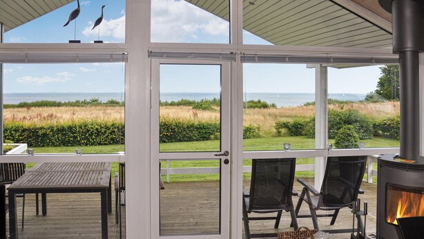 A covered outdoor area with a view of the sea, a wooden deck, and a wood-burning stove.