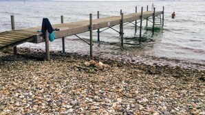 A wooden pier extending into calm water, with a rocky shore in the foreground.