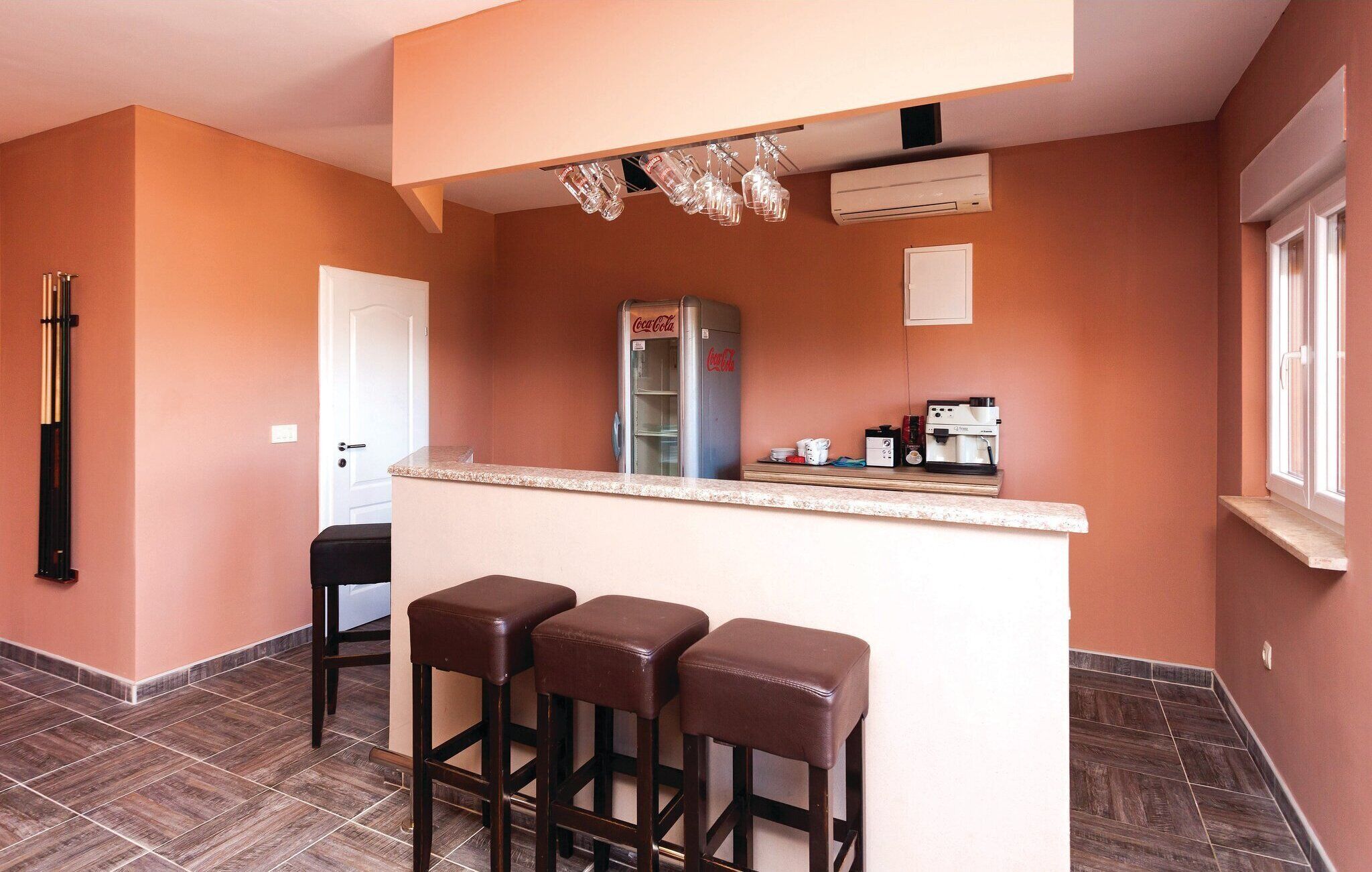 Una cucina compatta con angolo bar, frigorifero e macchina per caffè.