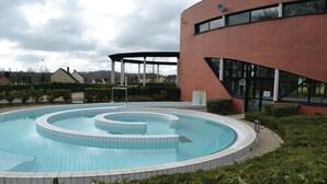 A swimming pool with a circular design, surrounded by a brick building and greenery. - 4 bedroom gorgeous home in Parfondeval (Parfondeval)