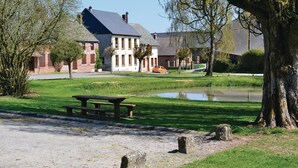A park with a picnic table, a pond, and a building with a sloped roof. - 4 bedroom gorgeous home in Parfondeval (Parfondeval)