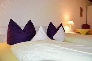 A bed with white and purple pillows, a lamp, and a wooden chair. - Double room Hollerbeerl - Hof Roßruck (Fischbachau)