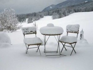 A snow-covered outdoor seating area with a table and two chairs. - Double room Hollerbeerl - Hof Roßruck (Fischbachau)
