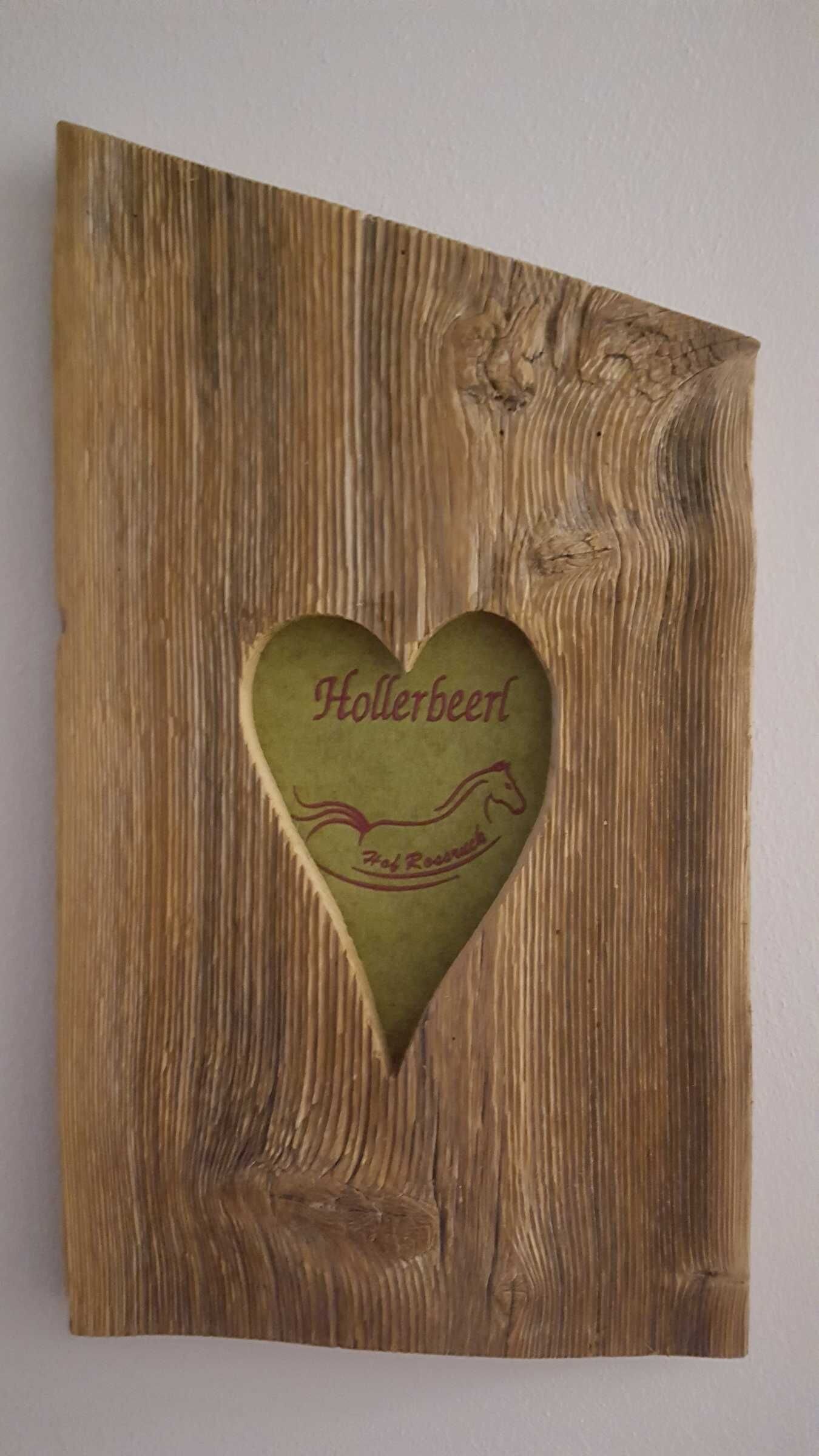 A wooden wall with a heart-shaped cutout containing the text 'Hollerbeer' and a horse silhouette.