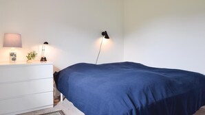 Une chambre à coucher avec un lit simple, une commode blanche et deux lampes fixées au mur.