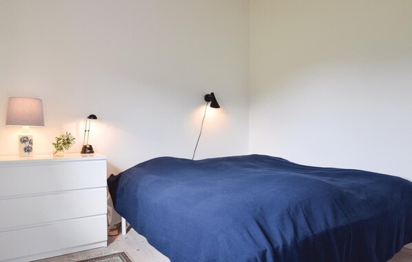Une chambre à coucher avec un lit simple, une commode blanche et deux lampes fixées au mur.