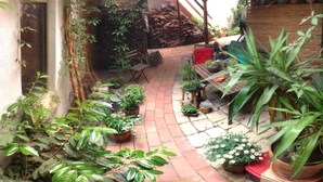Un patio cubierto con una mesa de madera, sillas y varias plantas en macetas.