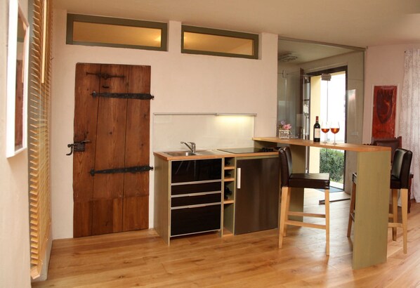 Una cocina compacta con puerta de madera, una pequeña encimera y una zona de comedor con dos sillas.