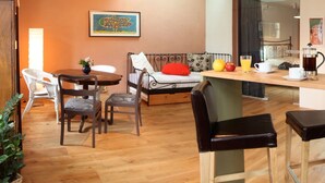 Un espacio de sala acogedor con sofá, mesa de comedor, sillas y una estación de café.