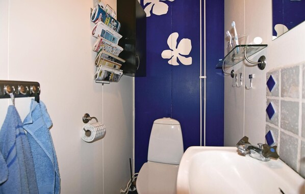 Un baño con inodoro, lavabo y toallero con una toalla azul.