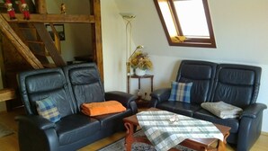 Un salon avec deux canapés en cuir noir, une table basse en bois et un tapis à motifs.