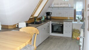 Une cuisine équipée d’une table à manger, de chaises, d’une machine à café et d’un four.