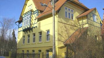 A two-story building with a yellow facade, multiple windows, and a red-tiled roof.