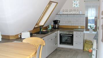 A kitchen with a dining table, chairs, a coffee maker, and an oven.