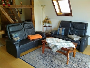 A living room with two black leather sofas, a wooden coffee table, and a patterned rug.