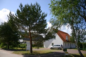 A white building with a red roof, surrounded by trees and a parked car. - Apartment 1 floor - house gallery (Karlshagen)