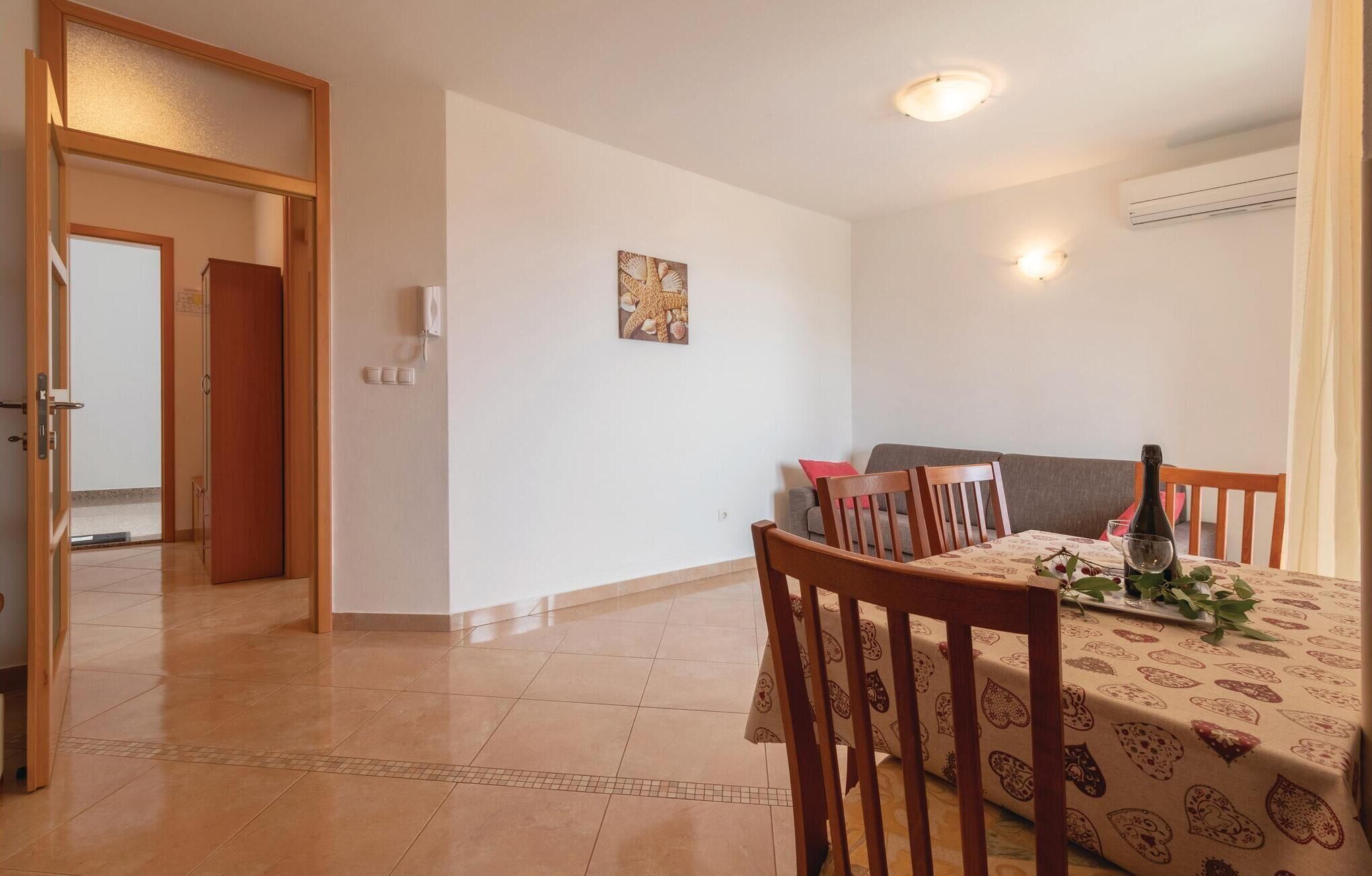 Un coin repas avec une table dressée pour deux personnes, un canapé et une porte donnant sur une autre pièce.