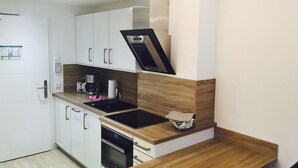 A compact kitchen with white cabinets, a black induction cooktop, and a built-in oven. - Stunning apartment in Binz with outdoor swimming pool (Prora/Rügen)