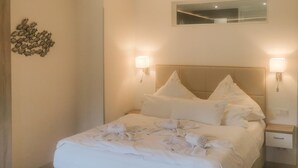 A neatly made bed with white linens and pillows, two bedside lamps, a small bedside table, and a wall decoration of fish. - Stunning apartment in Binz with outdoor swimming pool (Prora/Rügen)