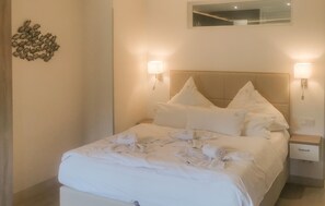 A neatly made bed with white linens and pillows, two bedside lamps, a small bedside table, and a wall decoration of fish. - Stunning apartment in Binz with outdoor swimming pool (Prora/Rügen)