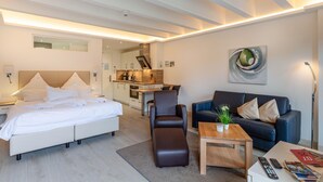 A modern hotel room with a bed, a sofa, a coffee table, and a dining area. - Stunning apartment in Binz with outdoor swimming pool (Prora/Rügen)