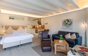 A modern hotel room with a bed, a sofa, a coffee table, and a dining area. - Stunning apartment in Binz with outdoor swimming pool (Prora/Rügen)