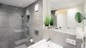 A modern bathroom with a glass-enclosed shower, a white sink, and a large mirror. - Stunning apartment in Binz with outdoor swimming pool (Prora/Rügen)