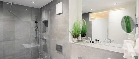 Une salle de bain moderne avec une douche à parois de verre, un lavabo blanc et un grand miroir.