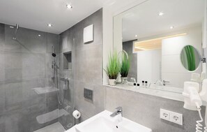 A modern bathroom with a glass-enclosed shower, a white sink, and a large mirror. - Stunning apartment in Binz with outdoor swimming pool (Prora/Rügen)