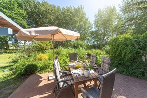 Une terrasse extérieure avec une table, des chaises et un parasol.