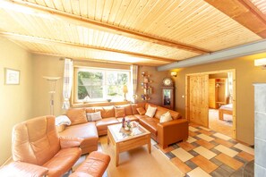A spacious living room with a large sofa set, a coffee table, and a wooden ceiling. - Holiday EC - Apartments in thatched house (Ummanz)