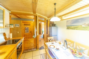 A wooden interior with a kitchen, dining area, and a view of the sea. - Holiday EC - Apartments in thatched house (Ummanz)
