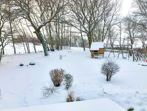 A snow-covered landscape with a wooden playhouse and swings.
