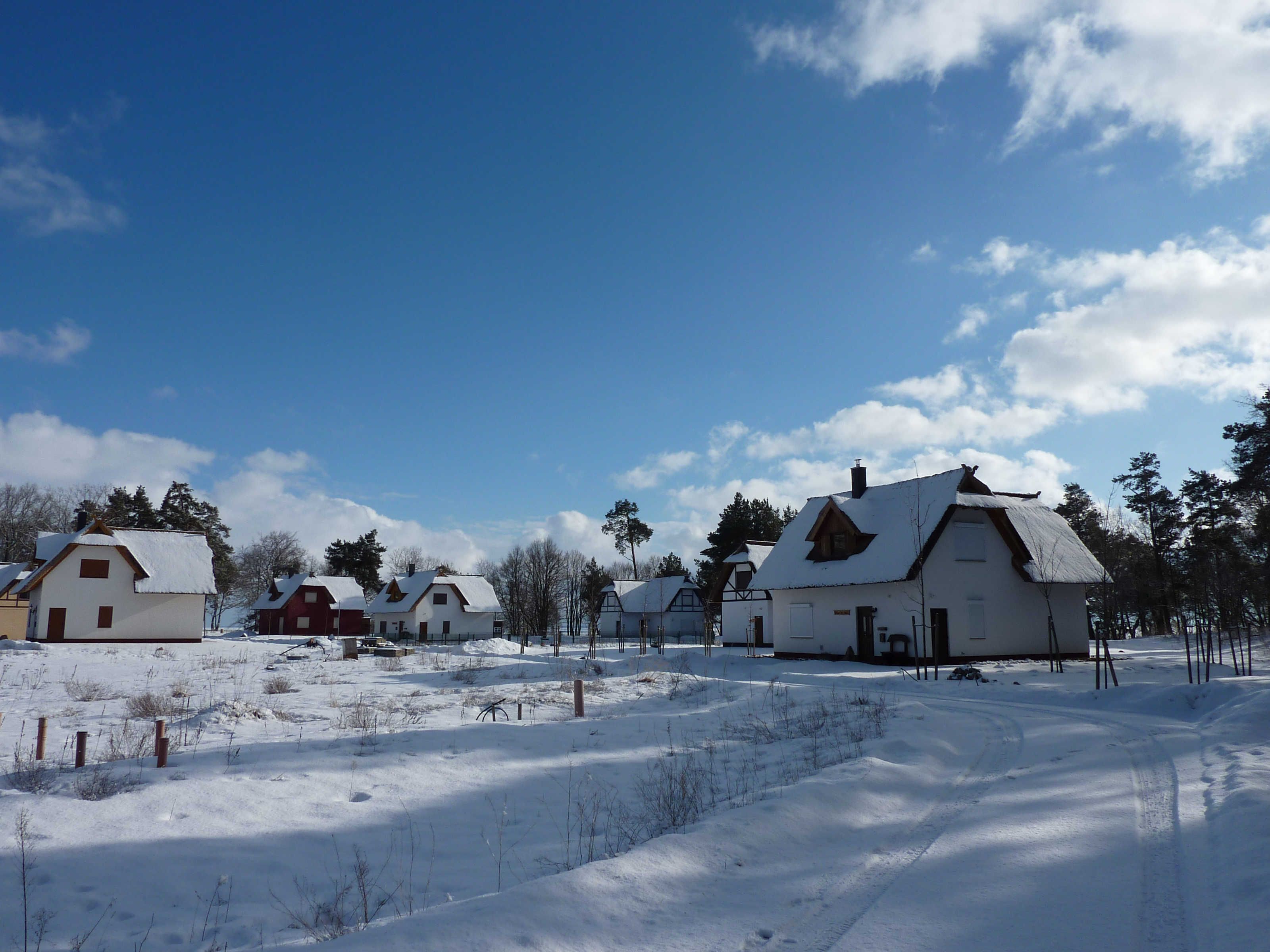 Un pueblo cubierto de nieve con casas tradicionales y un cielo azul despejado.