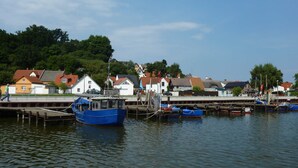 Un puerto con barcos amarrados, un muelle y casas al fondo.