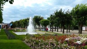 Un parque público con una fuente, macizos de flores y árboles.
