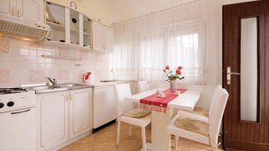 A kitchen with white cabinets, a stove, and a dining area with a table set for two.