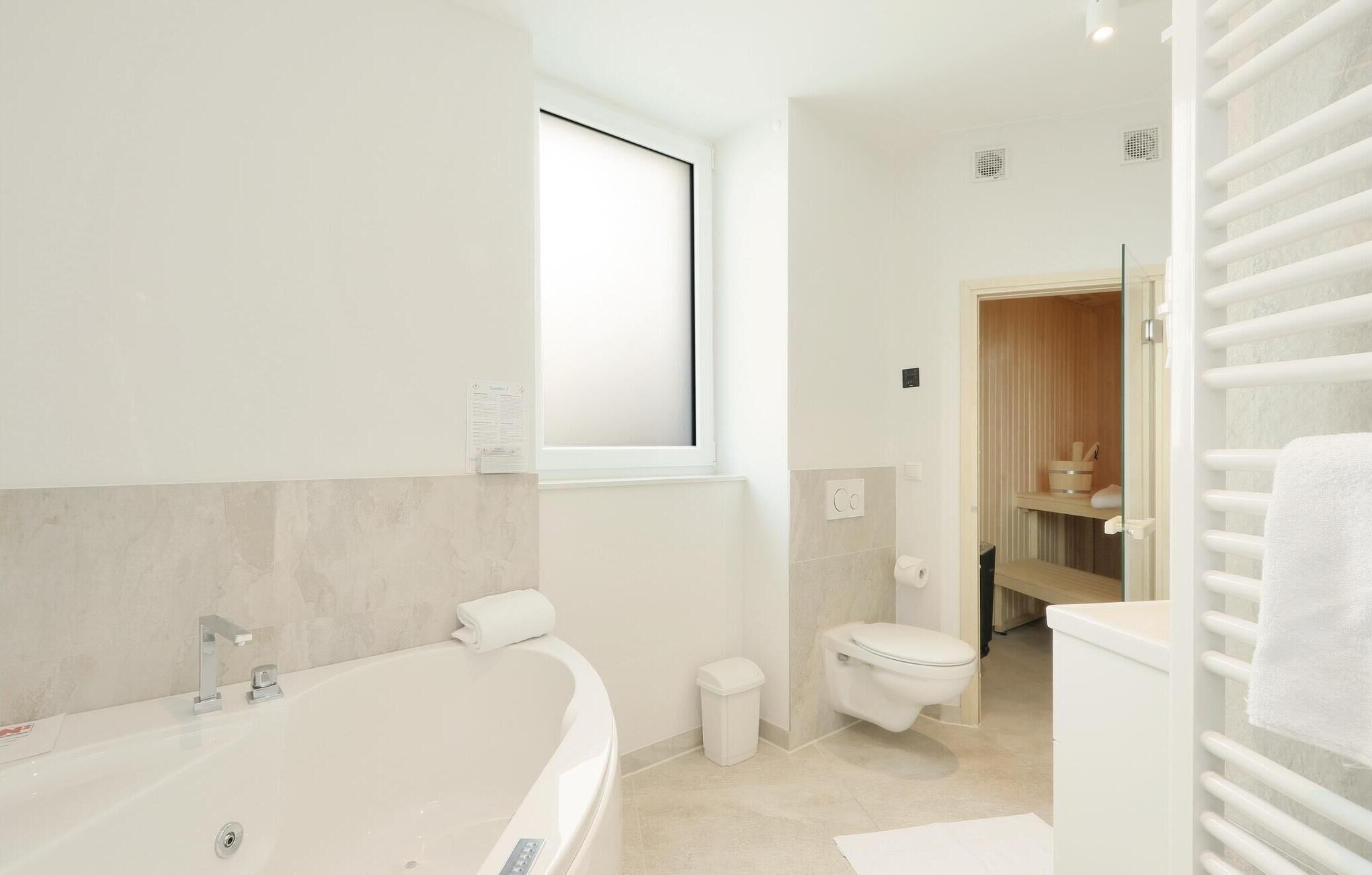 Un bagno moderno con una vasca autonoma, un water e uno spazio doccia.