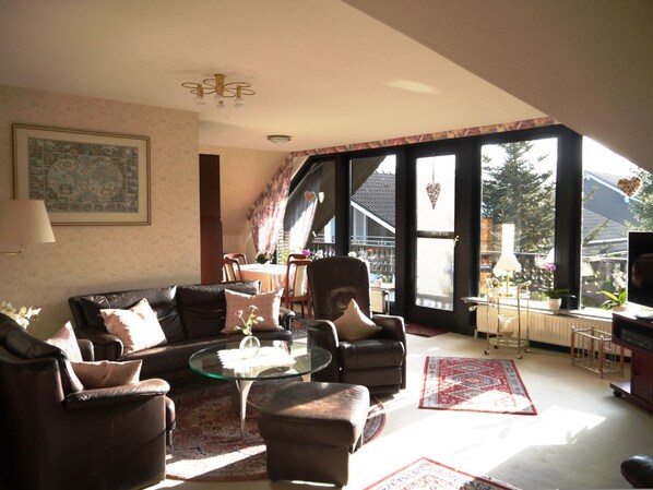A living room with a sofa set, a glass coffee table, and a dining area with chairs and a table.