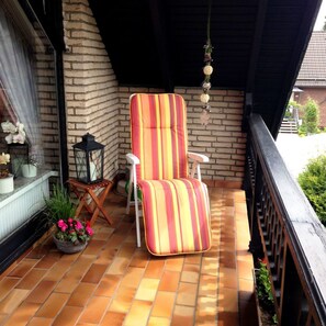 A balcony with a striped chair, a lantern, and potted plants. - Vacation apartment Will, Germany (Walkenried)