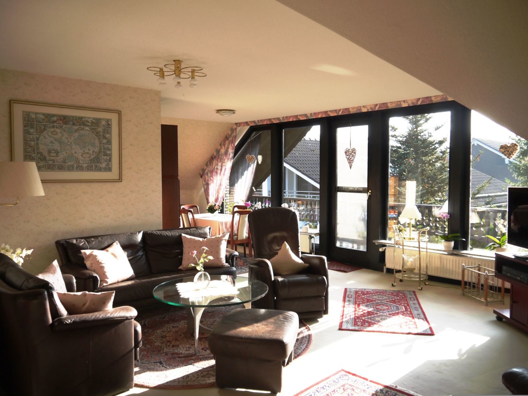 A living room with a sofa set, a glass coffee table, and a dining area with chairs and a table.