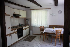 Eine Küche mit weißen Schränken, einem Herd und einem Essbereich mit Tisch und Stühlen.