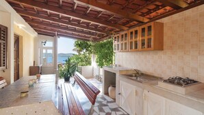 Cocina con vista al mar, vigas de madera en el techo y un banco en el centro.