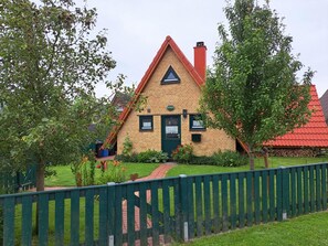 Une maison traditionnelle avec un toit rouge, une porte verte et une façade en briques.