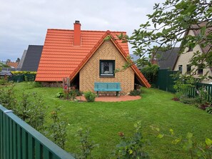 A small house with a red roof, a brick exterior, and a blue bench in the front yard. - House "Deichkind" - House "Deichkind" (Friedrichskoog)
