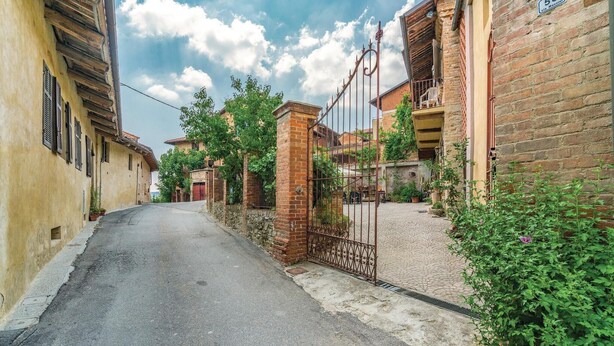 A narrow street with a cobblestone path, brick buildings, and a metal gate. - Cozy home in Aramengo (AT) (Aramengo (AT))