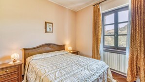 A bedroom with a bed, nightstands, a lamp, a framed picture on the wall, and a window with curtains. - Cozy home in Aramengo (AT) (Aramengo (AT))