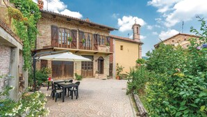 A courtyard with a table and chairs, surrounded by buildings with balconies and a chimney. - Cozy home in Aramengo (AT) (Aramengo (AT))