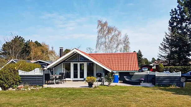 Een gelijkvloers huis met een rode pannendak, een overdekte patio en een omheinde tuin.